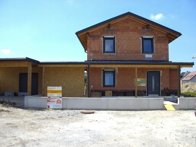 Carport mit Holzstützen an einem Rohbau-Haus