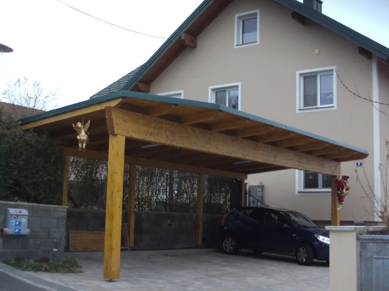 Carport mit Pultdach und Holzsäulen vor einem Wohnhaus