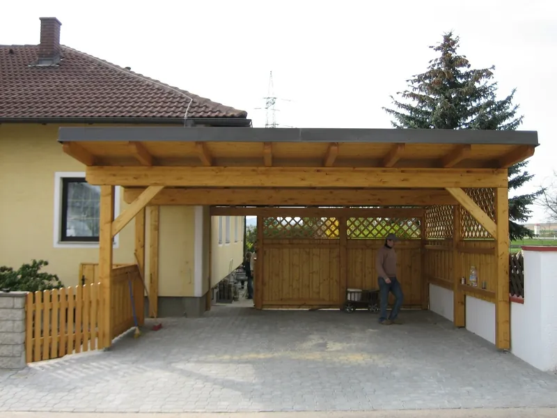 Carport mit Holzgitter und Zaun neben einem Wohnhaus