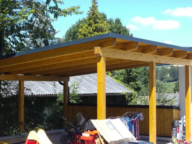 Carport mit Pultdach und gelb lasierten Holzstützen