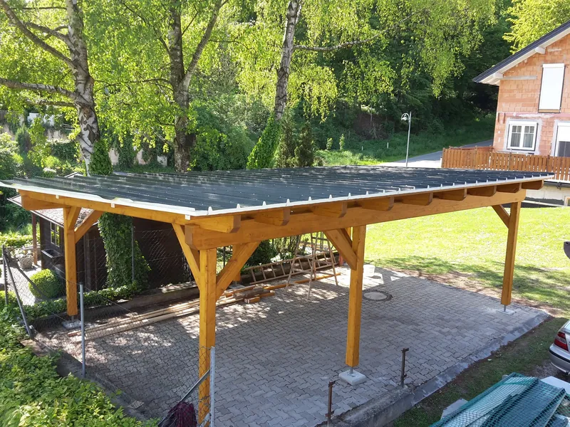 Carport mit Pultdach auf einer Pflasterfläche im Garten