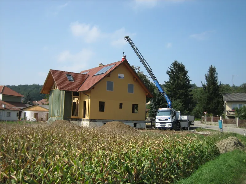 Holzhaus mit Dacheindeckung und Autokran