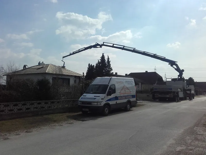 Autokran mit Material vor einem Haus bei der Dachsanierung