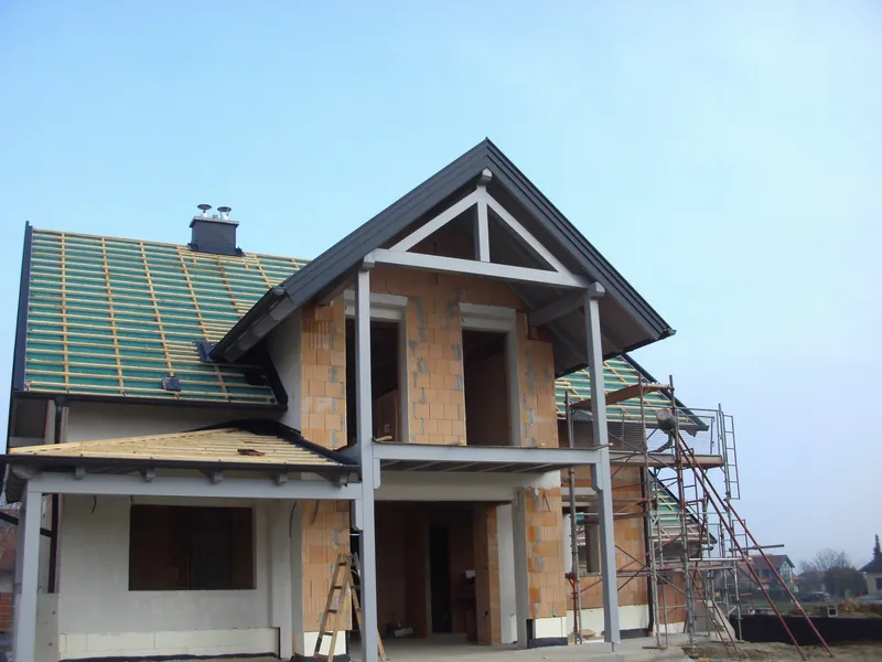 Rohbau mit Dachstuhl und Vordach aus Holz, im Gerüst