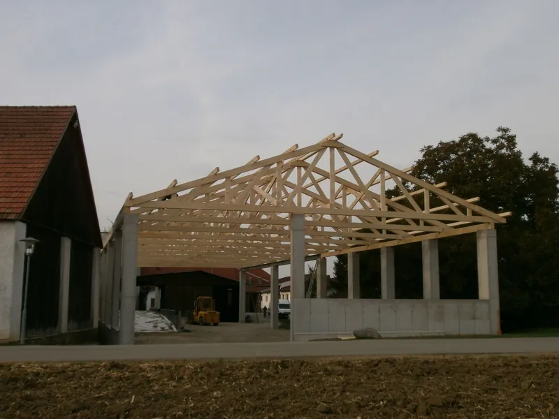 Hallenbau mit Holzbindern neben einem Stallgebäude
