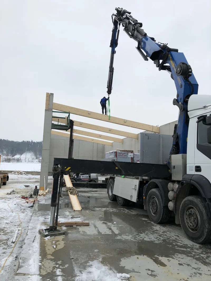 Montage eines Holzträgers mit Autokran im Winter