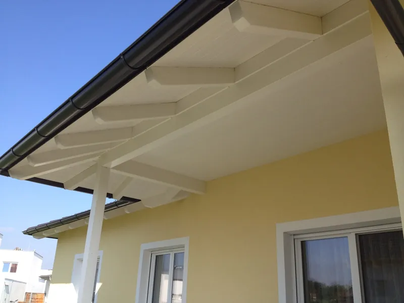 Überdachung mit weißer Holzuntersicht an einem gelben Haus