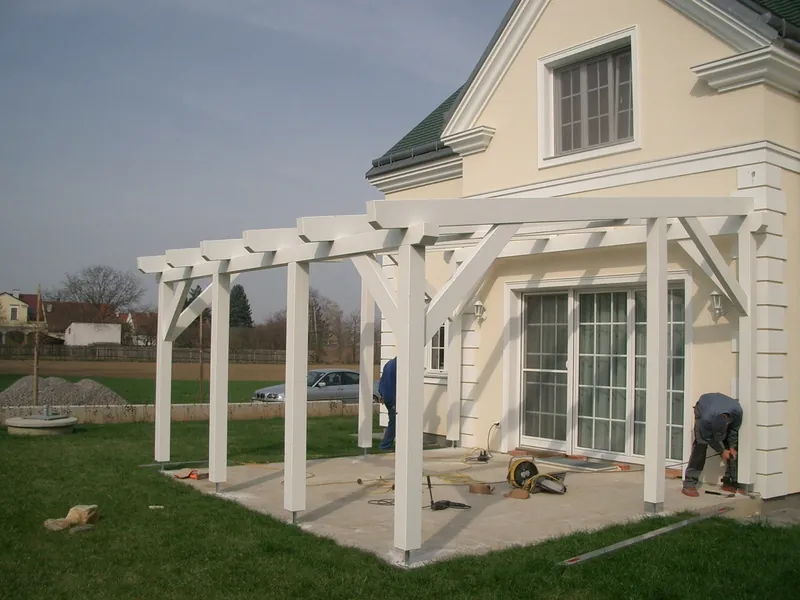 Weiße Pergola vor einem Wohnhaus mit Terrassentür