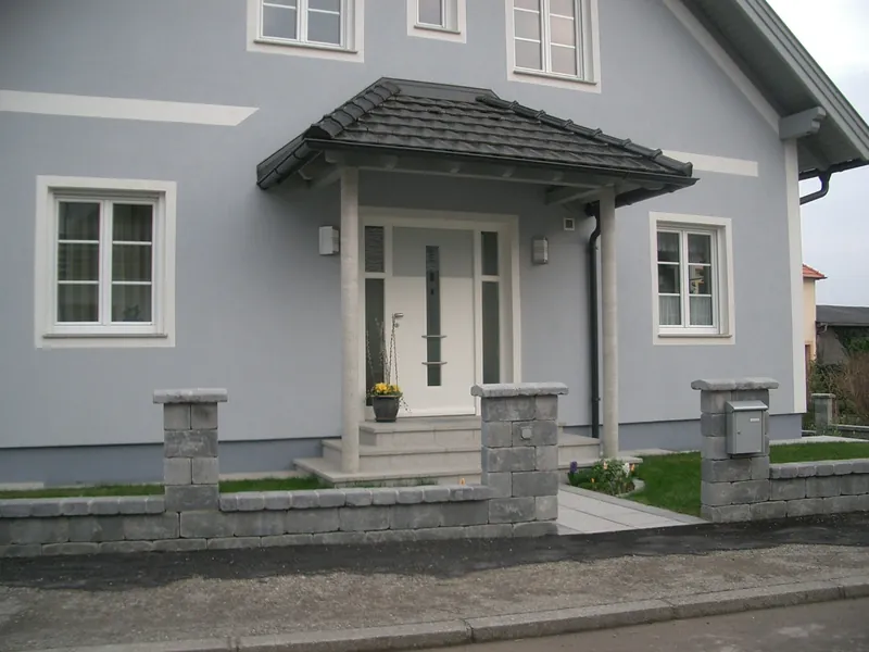 Vordach über der Haustür eines grau verputzten Hauses